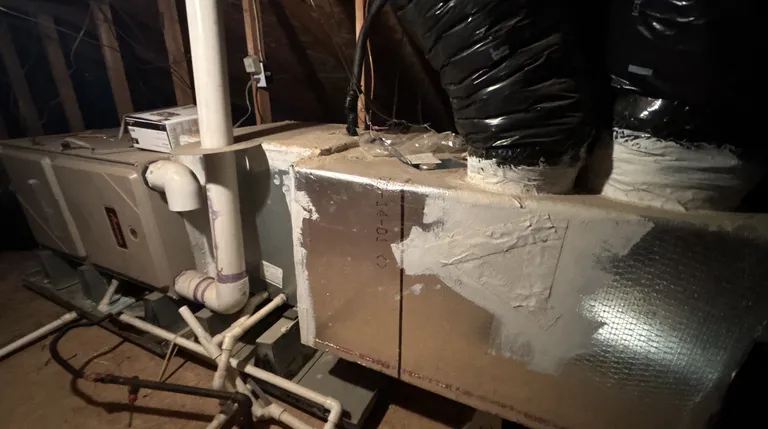 An attic HVAC system on a Sacramento service call: gas furnace on the left, evaporator coil cabinet and insulated supply plenum on the right feeding the ducts