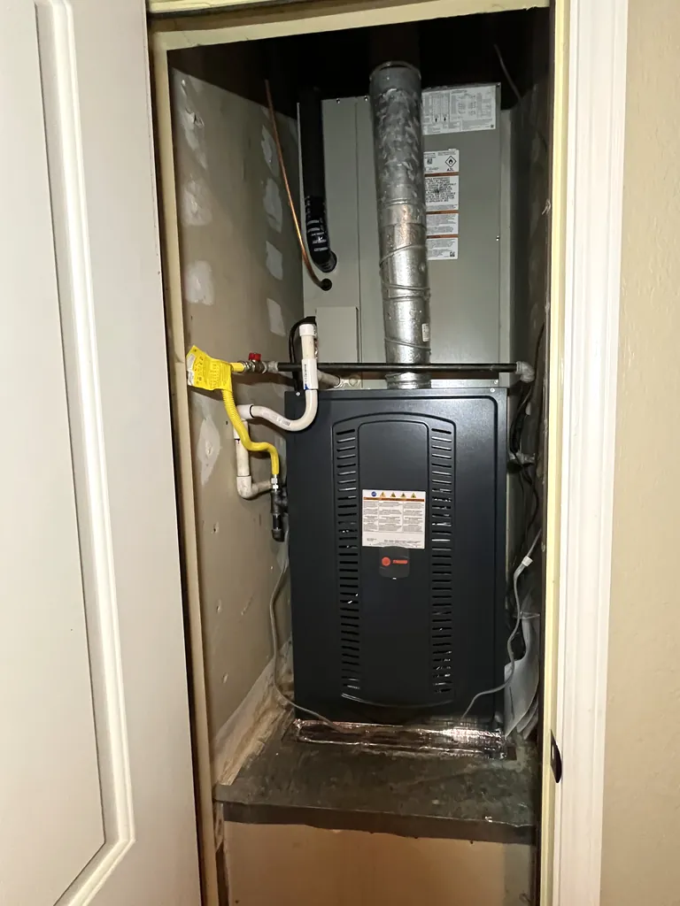 A new Trane gas furnace with its matching indoor coil cabinet above it, installed in a hall closet on a Roseville system replacement in August 2026