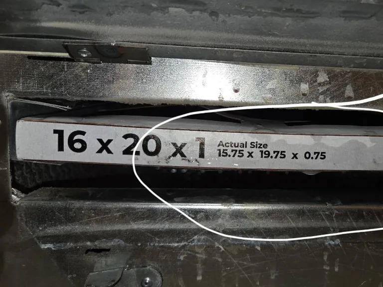 The edge of an air filter in its slot on an Alpha Mechanical service call in Sacramento in August 2026, printed with its nominal size, 16 x 20 x 1, and its actual size, 15.75 x 19.75 x 0.75, circled by the technician