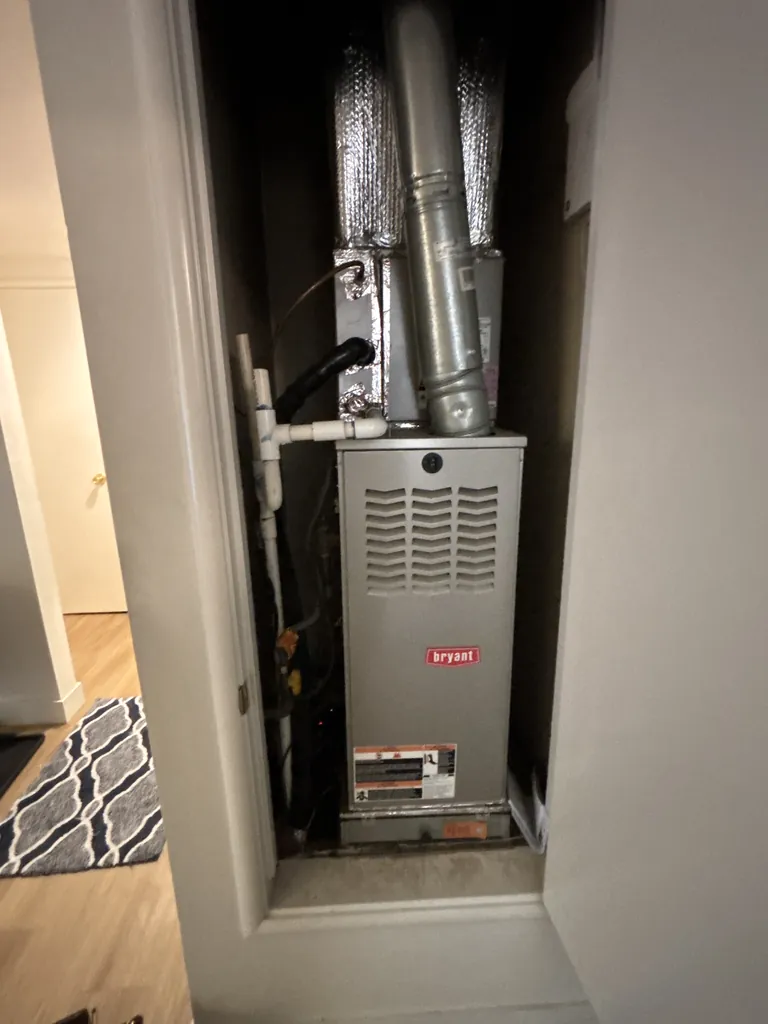 A Bryant upflow gas furnace in a hallway closet on an Alpha Mechanical service call in Sacramento in June 2026, panels on and the closet door open