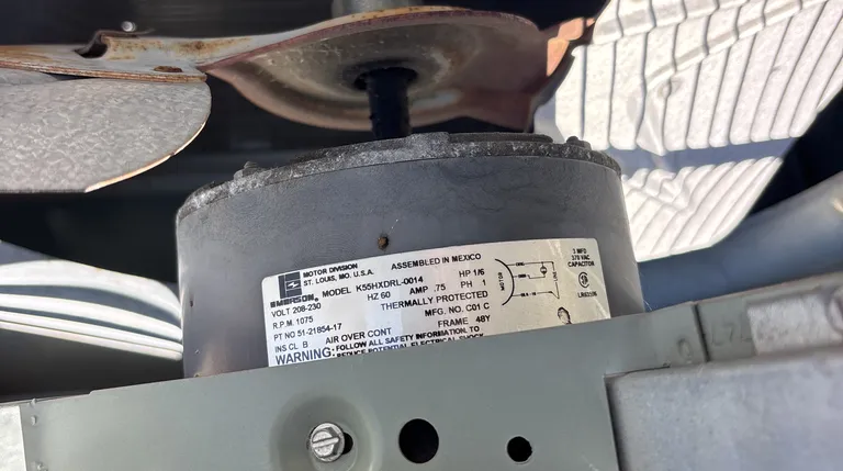 Close-up of a condenser fan motor pulled during a Sacramento service call, its spec label showing 1/6 HP, 208-230 V, 1075 RPM, and the 3 MFD 370 VAC run capacitor it requires