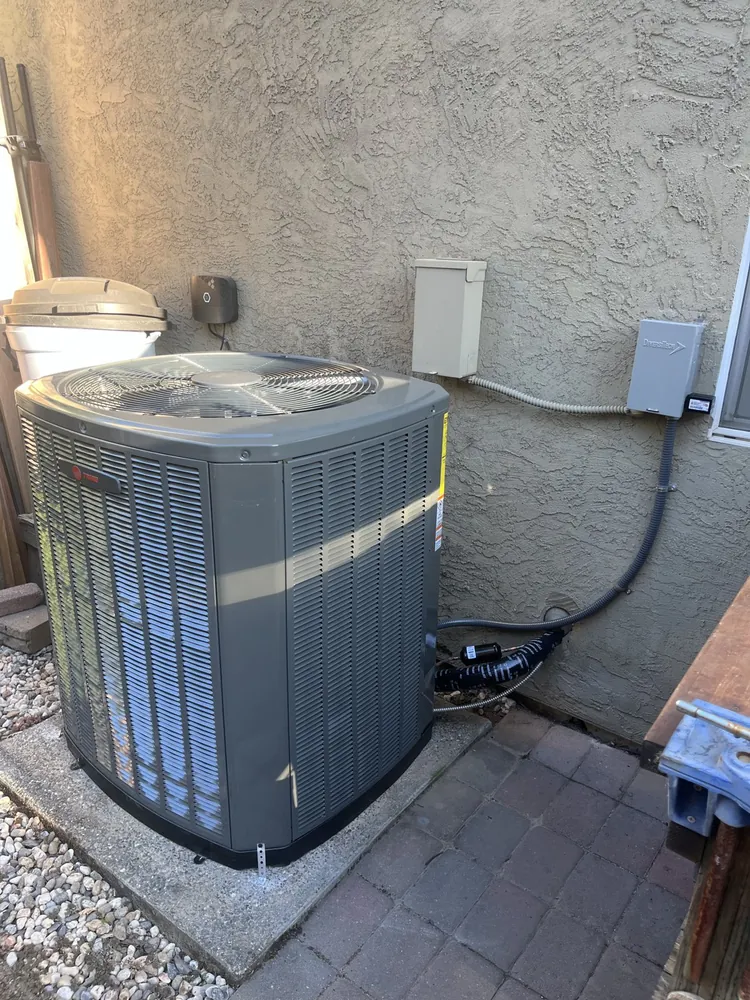 New Trane condenser on a concrete pad with line set and disconnects
