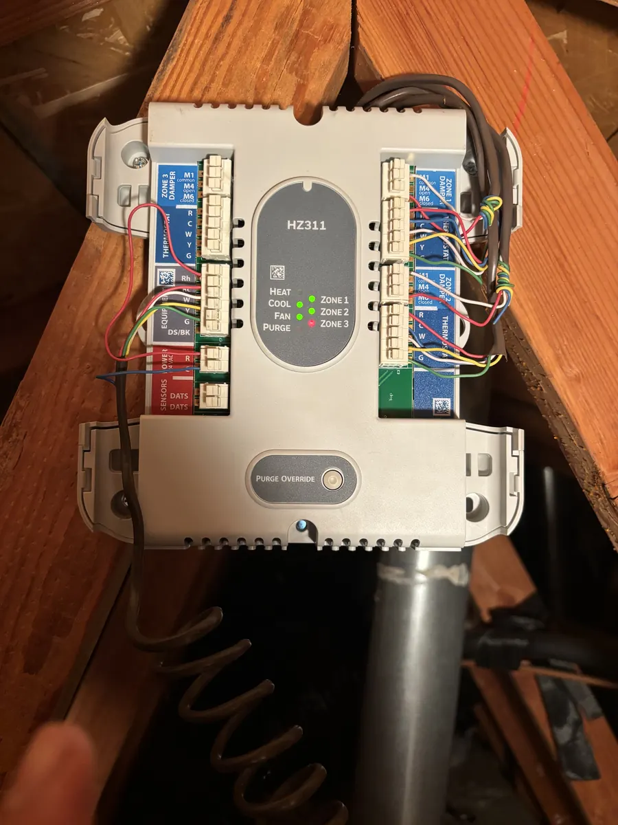 Honeywell TrueZONE HZ311 three-zone control panel with the cover off, damper and thermostat wiring on its terminal blocks, mounted in an attic